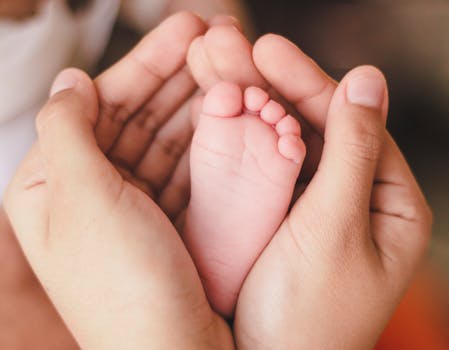 A tender moment capturing a newborn foot in warm adult hands, symbolizing love and care.