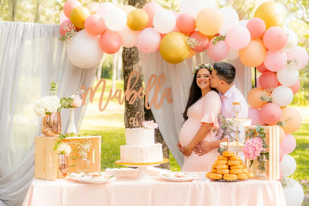 Joyful couple celebrating a baby shower with a lovely dessert table and pastel decor.