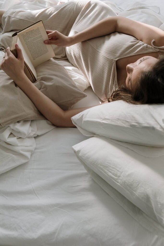 A serene image of a pregnant woman reading a book while lying in bed.