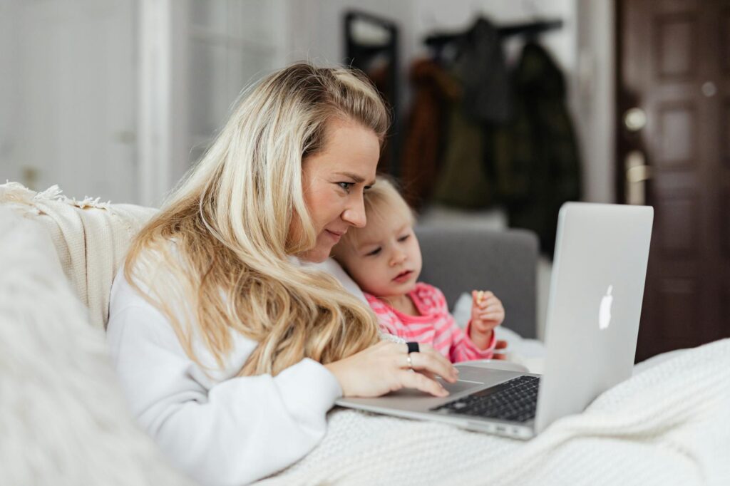 A mother and her daughter enjoy quality time together using a laptop indoors.