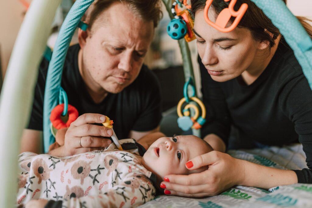 A couple attentively checking their baby's temperature with a thermometer indoors.