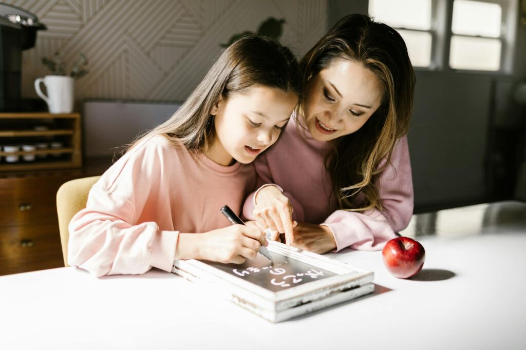 A mother and daughter collaborate on a school project at the kitchen table, fostering learning and creativity.