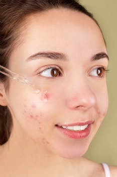 Close-up of a young woman applying serum on her face for acne treatment and skincare routine.